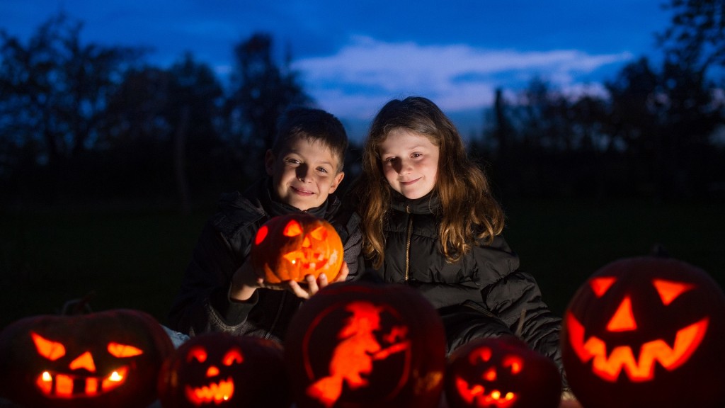 Zwei Kinder sitzen hinter ihren leuchtenden Kürbis-Gesichtern